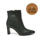 Bota corta de cuero negro con taco cuadrado y punta fina. Presenta una tira decorativa en el tobillo con una hebilla metálica que incluye el logo de la marca. Cuenta con cierre lateral.