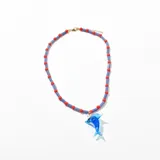 Collar corto con cuentas rojas y azules y dije de delfín de vidrio azul.