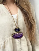 Collar largo con dije compuesto por dos piedras ágatas en tonos violeta y lila, engarzadas en bronce, con cordón de simil cuero en color marrón.