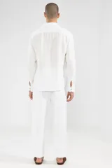 Camisa blanca de manga larga confeccionada en lino 100%, con calce recto y relajado. Presenta frente abotonado con botones de coco con logo y parche Polonio.