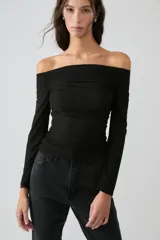 Top negro de microfibra traslúcida esmerilada, ajustado al cuerpo con mangas largas y hombros descubiertos con elástico en el escote.