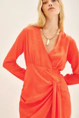 Vestido corto naranja vibrante de manga larga, con escote cruzado (cruzado) y detalle de nudo drapeado en la cintura. El tejido es de viscosa jacquard con un sutil patrón en relieve.