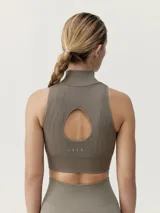 Top deportivo negro, cropped, de sujeción media, con cuello alto, cierre frontal con cremallera y espalda descubierta.