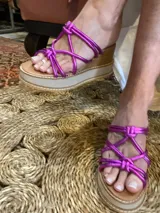 Sandalias de cuero color fucsia con tiras entrelazadas y plataforma de madera con suela de goma.