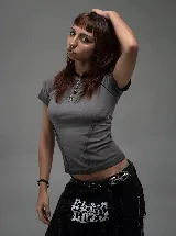 Remera de corte ajustado al cuerpo, color gris, con costuras decorativas visibles en el frente y mangas cortas.