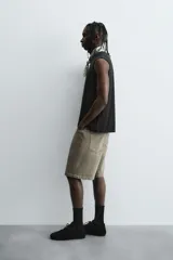 Bermuda de denim de algodón, color verde claro lavado, de corte recto y tiro medio. Presenta cinco bolsillos y cierre frontal con cremallera y botón.