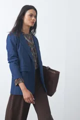 Blazer de jean color celeste con silueta recta y corte sastrero. Presenta solapas clásicas, cierre frontal con botón forrado, bolsillos con tapa y detalle de botones forrados en los puños.