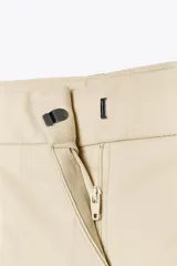 Bermuda color crema de tiro medio con pinzas delanteras y cinturón fino color beige. Tiene bolsillos frontales y falsos bolsillos de vivo en la espalda. Cierre frontal con cremallera, botón interior y gancho.