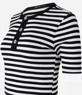 Blusa ajustada de mangas cortas, confeccionada en tejido de punto acanalado con rayas horizontales blancas y negras. Tiene cuello redondo con botones en la vista.