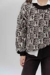 Buzo de tejido grueso con diseño artesanal bicolor en tonos marrón y crema. Presenta cuello redondo y terminaciones en rib en puños y cintura, con un calce relajado.