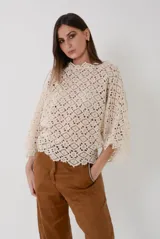 Buzo de crochet color crudo, con diseño geométrico calado, escote bote y mangas amplias cuadradas.