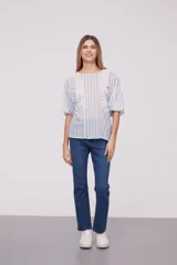 Blusa blanca con rayas verticales celestes, mangas abullonadas y detalles de calado en los hombros y el frente.