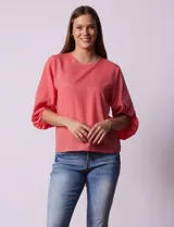 Blusa de gasa con estampado geométrico en tonos negro, gris y celeste. Tiene cuello redondo y mangas 3/4 amplias con abertura y botón.