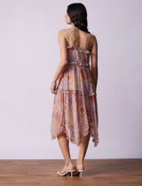 Vestido midi de gasa estampada con motivos geométricos en tonos naranja, lila y beige. Tiene breteles finos regulables, escote en V con volados y falda asimétrica con volados.