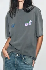 Camiseta de algodón con efecto lavado, corte oversize, cuello redondo y manga corta. Presenta estampados gráficos en el frente.
