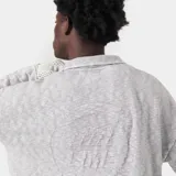 Sweater de punto gris con cuello polo y cierre frontal parcial. Presenta un diseño oversize y logo bordado en el frente.