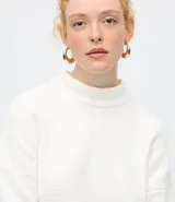 Suéter de punto texturizado con cuello alto, diseño oversized y mangas largas. Presenta una caída amplia y una superficie encorpada, ideal para un estilo moderno y acogedor.