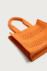 Bolso tipo shopper de color naranja con acabado trenzado y diseño estructurado. Cuenta con compartimento principal y dos asas cortas de mano.
