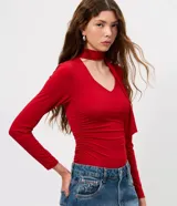 Blusa entallada de microfibra color blanco, con escote en V, mangas largas y detalle de frunces en los laterales. Presenta un lazo integrado en el cuello que permite anudarlo, aportando un toque sofisticado al diseño.