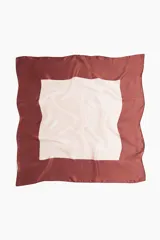 Pañuelo de seda con diseño de bloques de color. El centro es de color beige claro y el borde es de color bordó.
