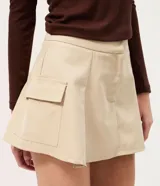 Short pollera beige de sarga con bolsillos cargo laterales y solapa, cintura ancha, pliegues delanteros y cierre frontal discreto.