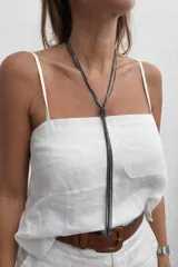 Collar largo tipo lazo, confeccionado con múltiples cadenas finas de metal plateado que se unen mediante un nudo central, creando un diseño minimalista y elegante.