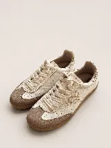 Championes de cuero con diseño urbano, combinando paneles de cuero texturizado en color crema con detalles en gamuza color tostado en la puntera. Presentan cordones al tono, suela de goma y un monograma bordado en el lateral, con un detalle de estampado animal print en el talón.