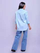 Camisa de manga larga a rayas verticales celestes y blancas, de corte suelto, confeccionada en algodón.