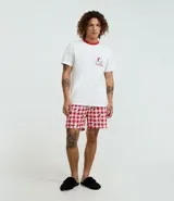 Pijama masculino de algodón, compuesto por una remera blanca de manga corta con cuello redondo y ribete rojo, y un short con estampado a cuadros rojos y blancos con figuras de Snoopy y Woodstock.