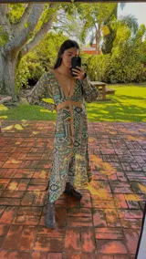 Vestido largo tipo abrigo con estampado geométrico en tonos beige, verde y azul. Presenta escote en V, cierre frontal con botones y detalles de franjas lisas en beige.