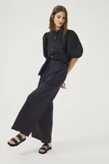 Pantalón culotte negro de lino orgánico, con cintura alta, diseño plisado y bolsillos laterales.