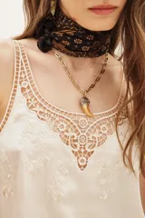 Top tipo musculosa de modal satén color crema, con detalle de encaje calado y bordados a tono en el escote delantero y en la espalda.