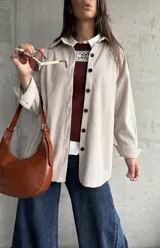 Sobrecamisa de pana color natural, con corte oversize, cuello camisero, cierre frontal de botones oscuros y mangas largas con puños abotonados.