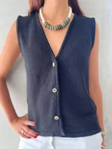 Chaleco negro de punto con cuello en V y cierre frontal con botones.