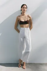 Jeans de tiro alto, pierna ancha y largo al tobillo, en denim celeste claro con efecto lavado. Presenta costura marcada en el centro de cada pierna y cierre frontal con cremallera y botón.