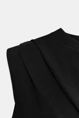 Top de punto negro con cuello redondo, manga sisa, hombreras y detalle de pliegues en la parte delantera.