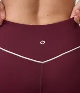 Pantalón legging deportivo Get Over de color bordó, confeccionado en microfibra elastizada con cintura alta y una línea vertical en contraste en el lateral.