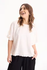 Blusa de lino color crudo, de manga corta con detalles de volados en las mangas y en el ruedo.