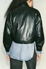 Bomber de efecto piel con cuello subido, manga larga y cierre frontal con botones a presión. Presenta bolsillos delanteros de vivo y bajo elástico en el delantero.
