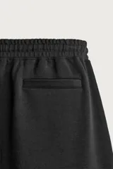 Bermuda estilo jogger de ajuste relajado, color negro, confeccionada en tejido interlock de algodón. Cuenta con cintura elástica ajustable mediante cordón, bolsillos delanteros tipo vivo y diseño liso.