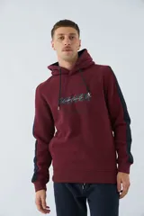 Buzo canguro color bordó con capucha y cordones negros. Tiene mangas largas con una franja vertical azul marino en los laterales y un estampado con texto en el pecho.