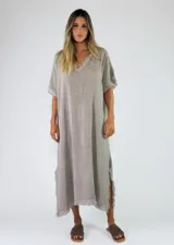 Vestido largo de algodón color gris, de corte holgado, mangas cortas y escote en V con detalles de flecos en los bordes y aberturas laterales.
