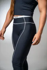 Calza deportiva larga negra con tiro alto y detalles de líneas blancas en los laterales.