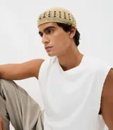 Gorro tipo beanie confeccionado en ganchillo de poliéster, con textura artesanal y diseño de puntos trabajados con detalle calado en la base.