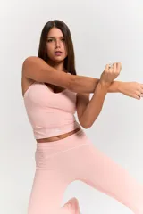 Conjunto deportivo de dos piezas en color rosa pastel. Incluye un top de escote redondo con espalda estilo nadadora y logo estampado en el frente, y una calza de tiro alto con costuras reforzadas a tono.