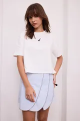 Falda corta de corte envolvente con diseño de gajos superpuestos y costuras a contratono en los bordes.