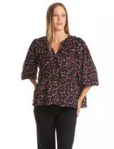 Blusa de gasa con estampado de corazones rojos y blancos sobre fondo negro. Presenta cuello redondo con escote en V, mangas largas con puños fruncidos y un corte holgado con detalle de frunces en la cintura.