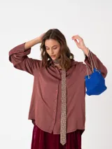 Camisa de raso color bordó con silueta suelta, manga larga, puños anchos y cierre frontal con botones a tono.