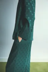 Pijama de dos piezas compuesto por camisa de manga larga con cuello camisero y botones frontales, y pantalón de corte recto y holgado con cintura elástica y cordón de ajuste. Presenta un diseño estampado con pequeños corazones en tono sobre tono.