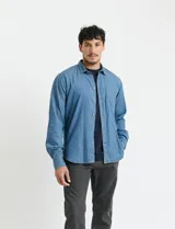 Camisa de denim de algodón con cuello clásico, cierre frontal con botones, bolsillo superior de parche y mangas largas con puños abotonados.